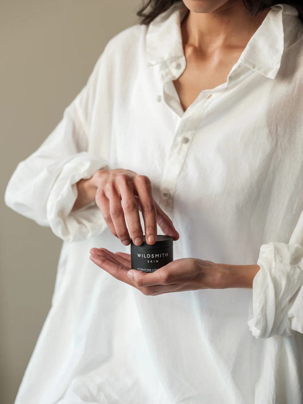 A jar of Wildsmith Skin Hydrating Light Cream held in both hands